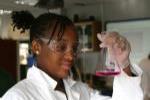 Teen wearing a lab coat working in chemistry class.